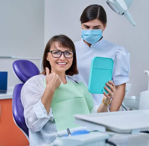 Happy patient next to dental assistant after smile recovery with custom dentures in Clearwater