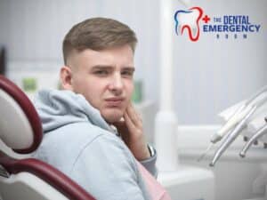 A young man in a dental chair appears to be in discomfort, touching his cheek possibly due to a broken molar, with dental tools in the foreground